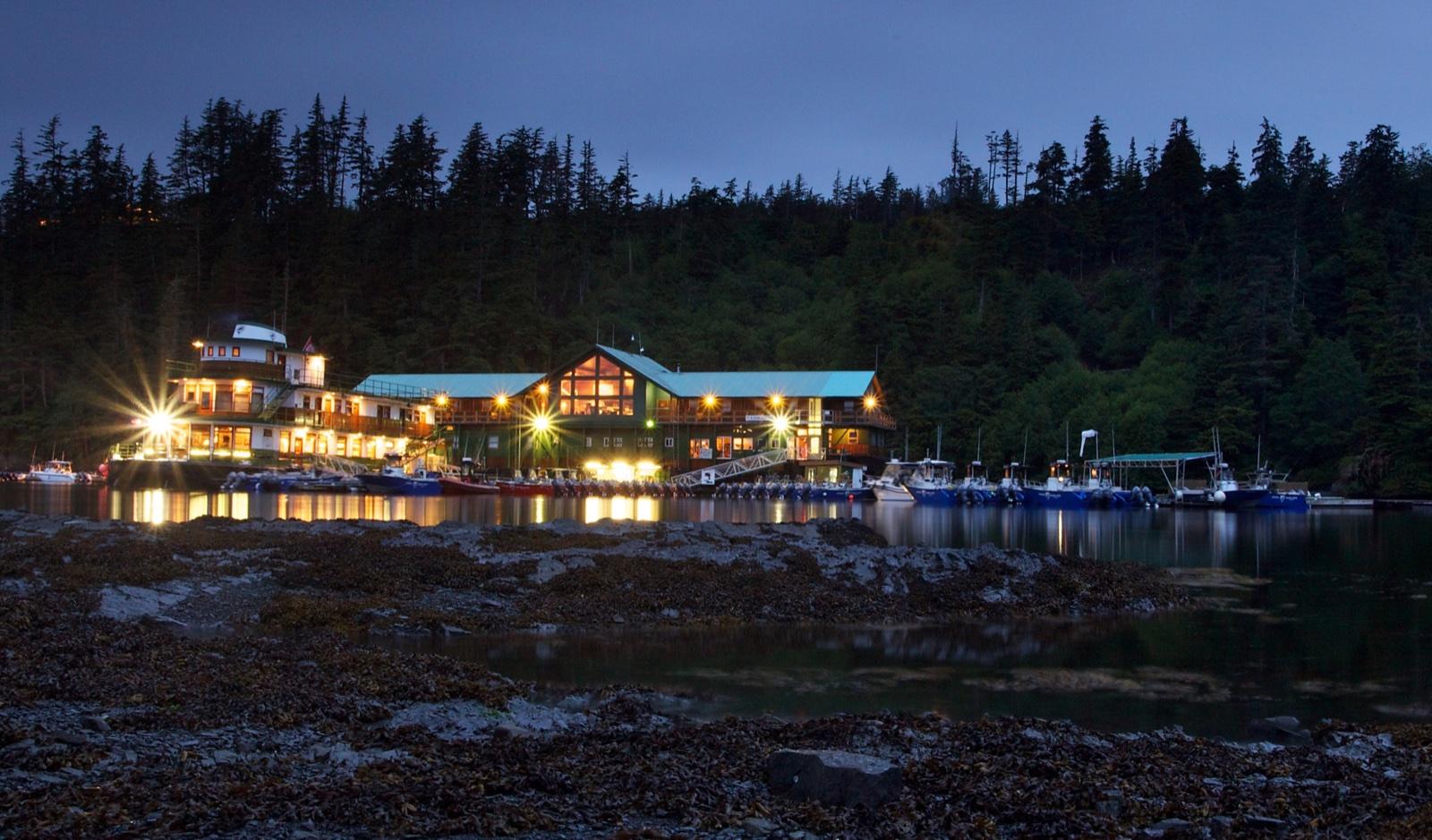 Langara Fishing Lodge lit up beside the water at dusk